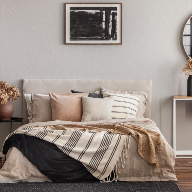 Abstract black oil painting in frame on empty beige wall of cozy bedroom