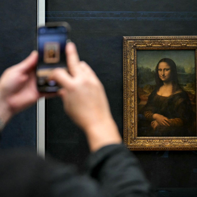 Posjetitelj fotografira Mona Lisu talijanskog umjetnika Leonarda Da Vincija u muzeju Louvre u Parizu 28. siječnja 2025. 