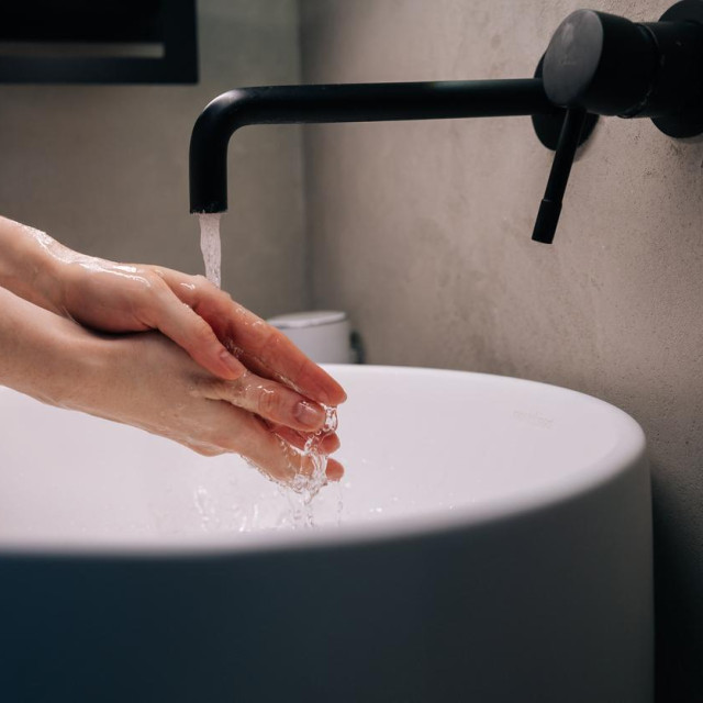 Bijeli umivaonik s crnom slavinom.