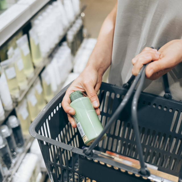 An anonymous female customer holding her basket while shopping on Black Friday.