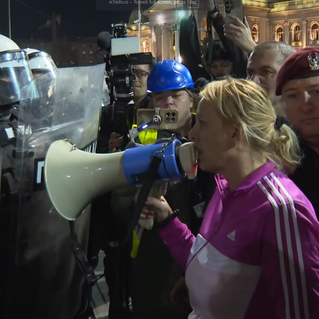 Dijana Hrka s megafonom stoji pred policajcima