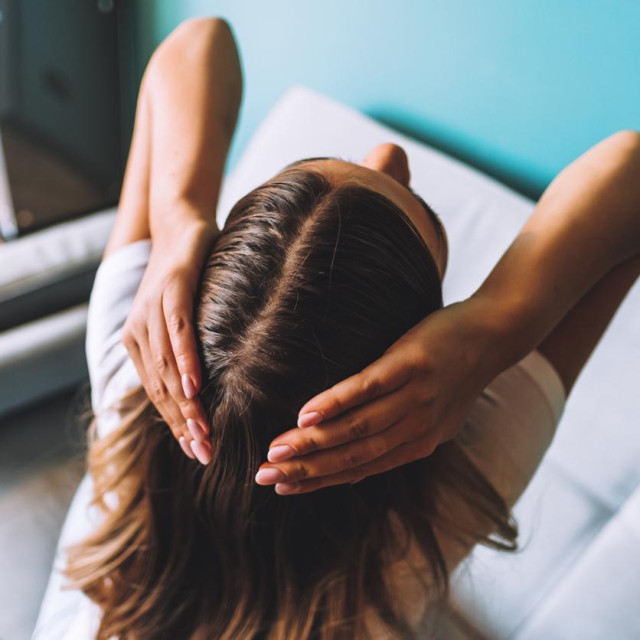 Young brunette woman showing her hair, hair roots, color, grey hair, hair loss or dry scalp problem.. High quality photo