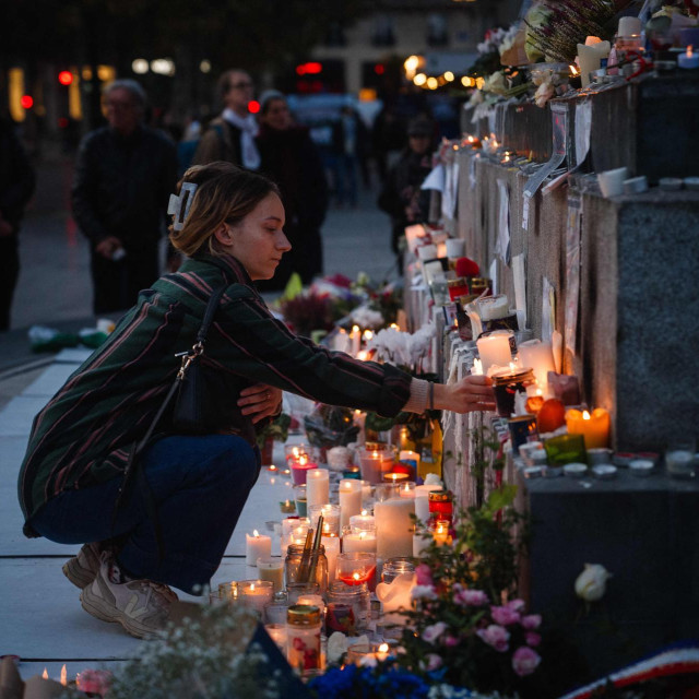 Žena pali svijeću u sjećanje na žrtve napada u Parizu 13. studenoga 2015.