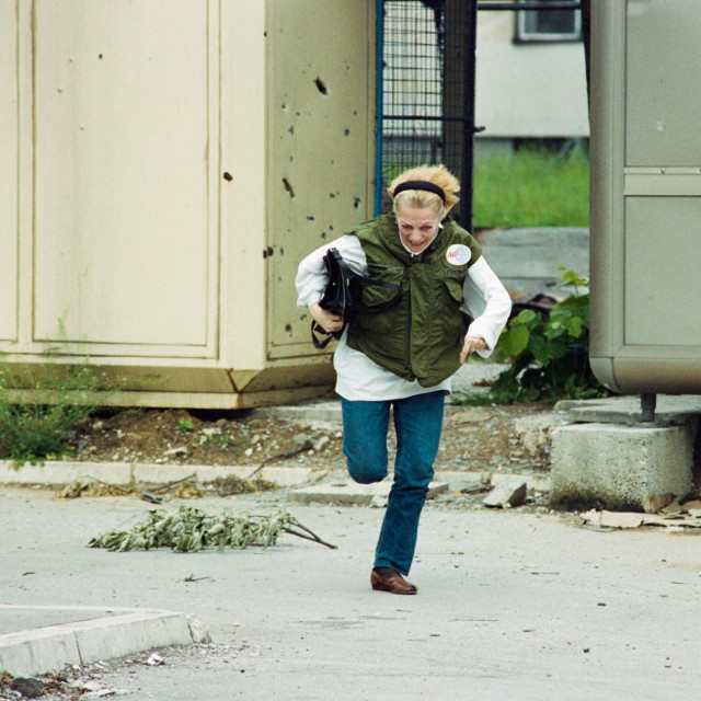 Žena s pancirkom trči tijekom oružanih sukoba u Sarajevu u lipnju 1992. godine