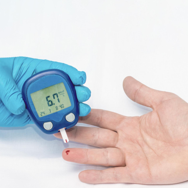 Nurse measures the blood sugar level of one patient.. The concept of diabetes. A blue-gloved hand. A little too high reading of blood sugar (6.7) Mmol International standard unit