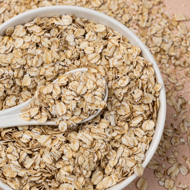 Dry uncooked oat flakes in a spoon top view