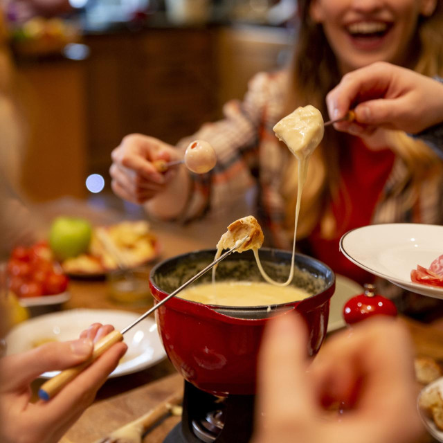 A group of work colleagues eat fondue together on a team bonding trip.
