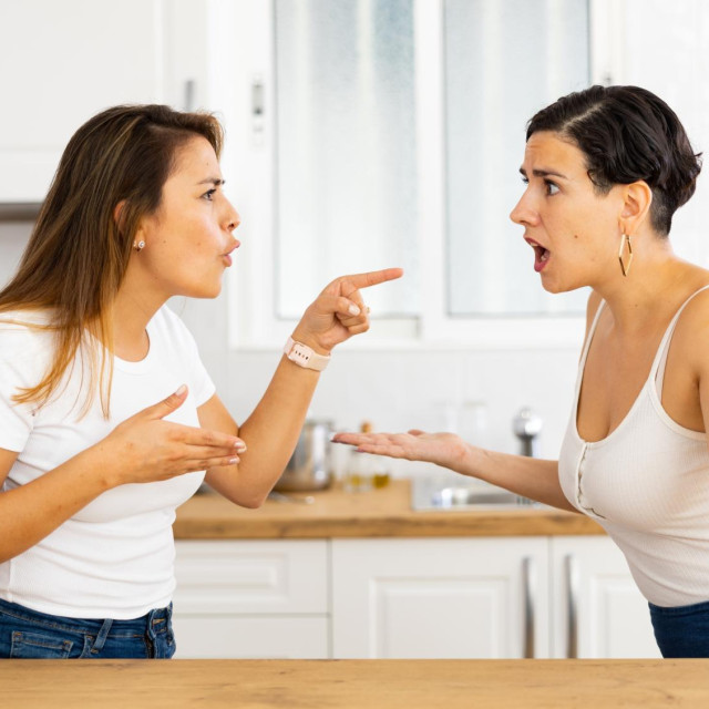 Female friends sorting out relationship. Two irritated young Latinas arguing noisily and emotionally gesturing in cozy home kitchen