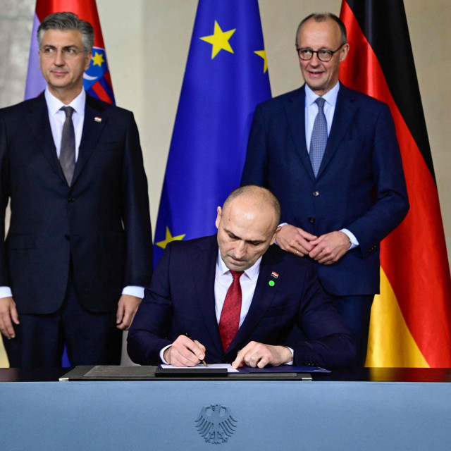 Hrvatski premijer i njemački kancelar iznad ministra Ivana Anušića koji potpisuje važan dokument
