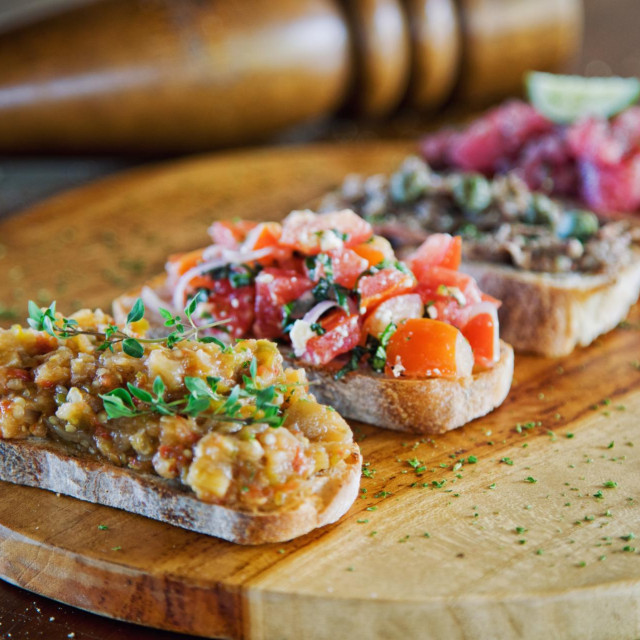 Bruschetta served on a french baguette with eggplant paste, tomatoes, chicken paste and minced raw tuna