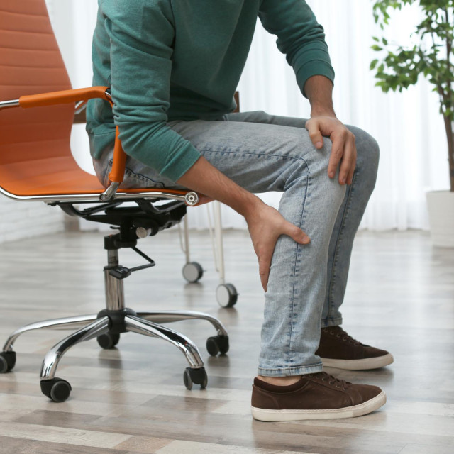 Man suffering from leg pain indoors, closeup