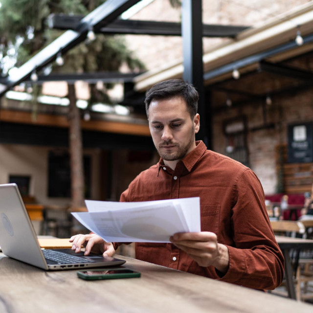 Photo of a young man working at coffee shop using modern technologies