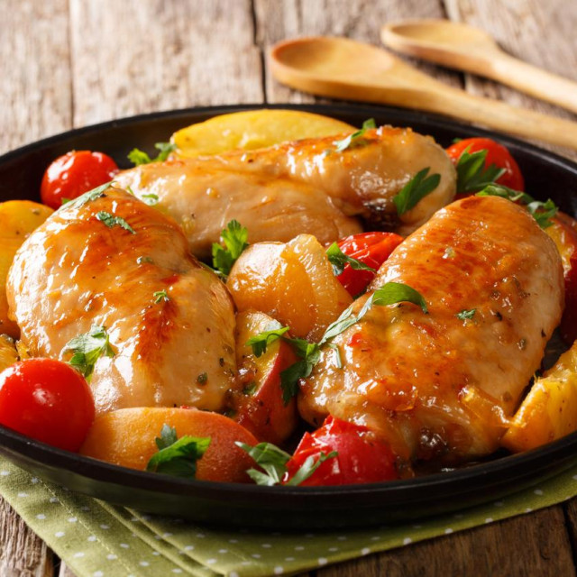 Summer food: chicken breast baked with fresh peaches, tomatoes, onions and honey garlic sauce close-up on a plate on a table. horizontal
