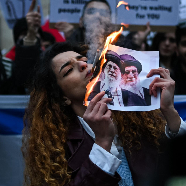 Prosvjednica protiv iranskog režima pali cigaretu zapaljenim papirom s likom iranskog vrhovnog vođe Alija Hamneija tijekom okupljanja ispred američkog konzulata u Milanu 13. siječnja 2026.