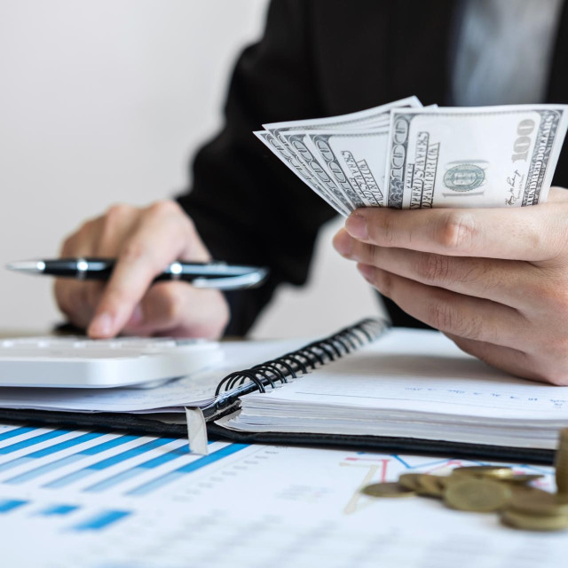 Businessman accountant counting money and making notes at report doing finances and calculate about cost of investment and analyzing financial data, Financing Accounting Banking Concept.