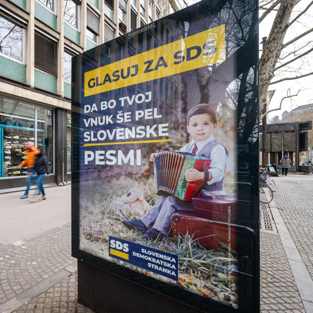 Prolaznici pored izbornog plakata stranke SDS uoči općih izbora u Sloveniji, u Ljubljani, 14. ožujka 2026. godine