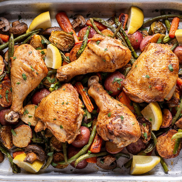 Roasted Chicken Thighs and Drumsticks over Carrots, Potatoes, Asparagus, Mushrooms, Green Beans and Brussels Sprouts, Garnished with Lemon