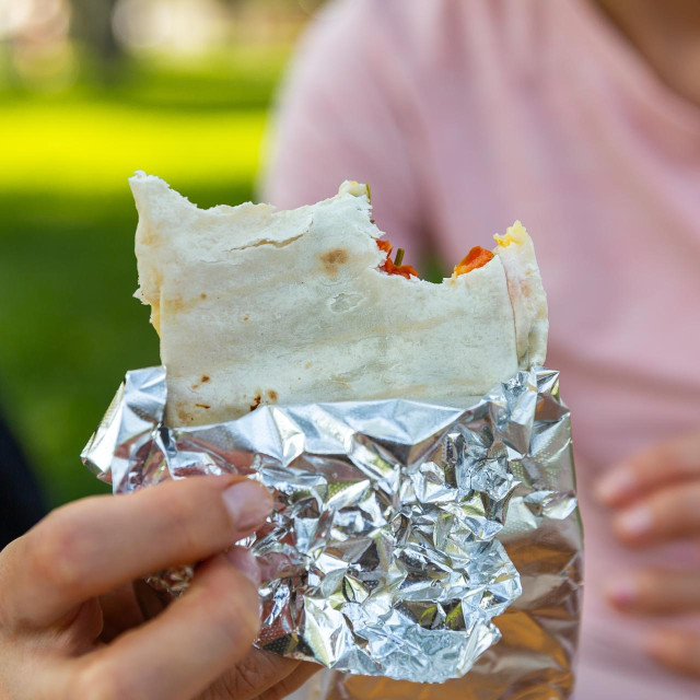 Close up of hands handling food outdoor. Woman hand holding deletions pita. Street food concept