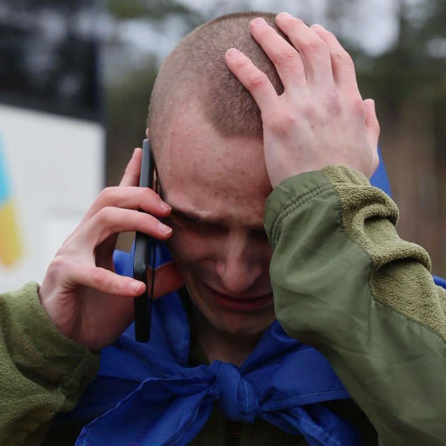 Bivši ukrajinski ratni zarobljenik, ogrnut nacionalnom zastavom, razgovara mobitelom nakon razmjene na nepoznatoj lokaciji, 11. travnja 2026. godine, tijekom ruske invazije na Ukrajinu