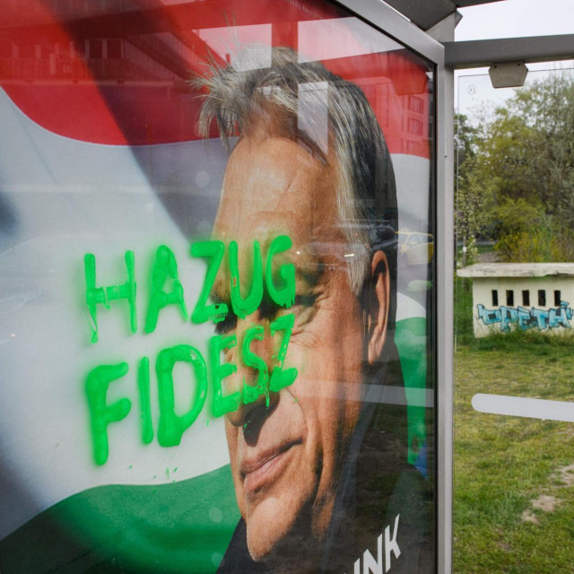 Natpis „Lažljivi Fidesz” prekriva plakat o nacionalnoj peticiji protiv rata s likom mađarskog premijera na odlasku i čelnika Fidesza Viktora Orbána na autobusnoj stanici u blizini Južnog željezničkog kolodvora u Budimpešti 13. travnja 2026., dan nakon općih izbora dok u pozadini leže razbacani plakati izborne kampanje