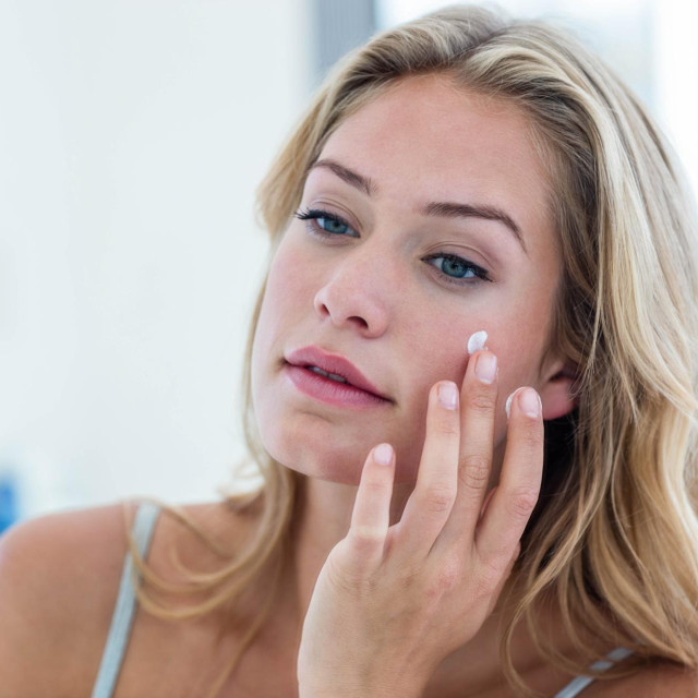 Smiling pretty woman applying cream on her face in bathroom,Image: 280469850, License: Royalty-free, Restrictions:, Model Release: yes, Credit line: -/Wavebreak/Profimedia
