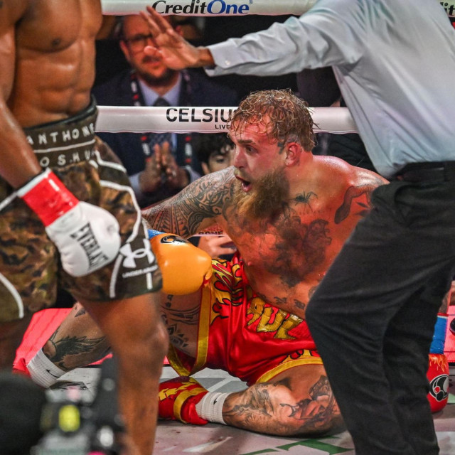 Referee Christopher Young counts over US boxer and influencer Jake Paul as he sits on the floor during his fight against British boxer Anthony Joshua (L) in a non-title heavyweight bout at the Kaseya Center in Miami, Florida, on December 19, 2025. (Photo by Giorgio VIERA/AFP)