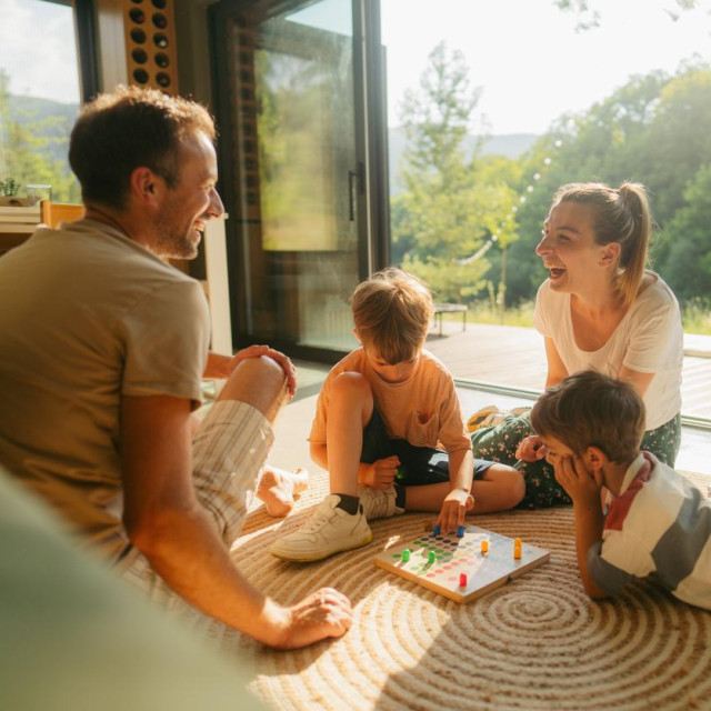 Photo of a young family playing board games together on the floor of their home