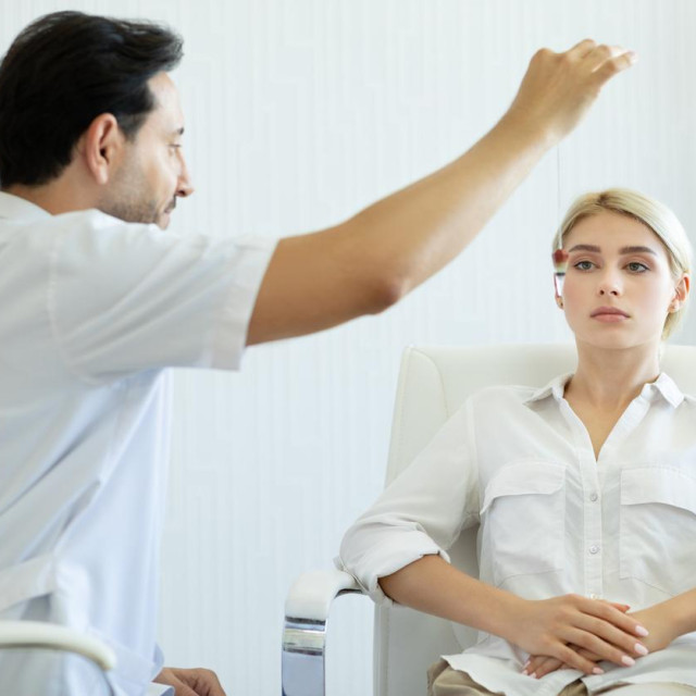 Male therapist using hypnosis therapy on young woman