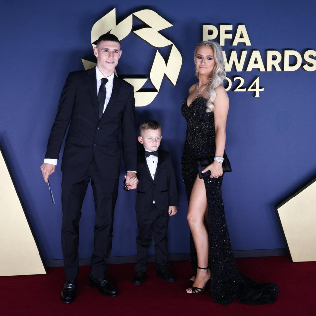 Manchester Cityjev engleski vezni igrač Phil Foden pozira na crvenom tepihu sa svojim sinom Ronniejem Fodenom i suprugom Rebeccom Cooke Foden po dolasku na dodjelu nagrada Udruge profesionalnih nogometaša (PFA) za sezonu 2023./2024.
