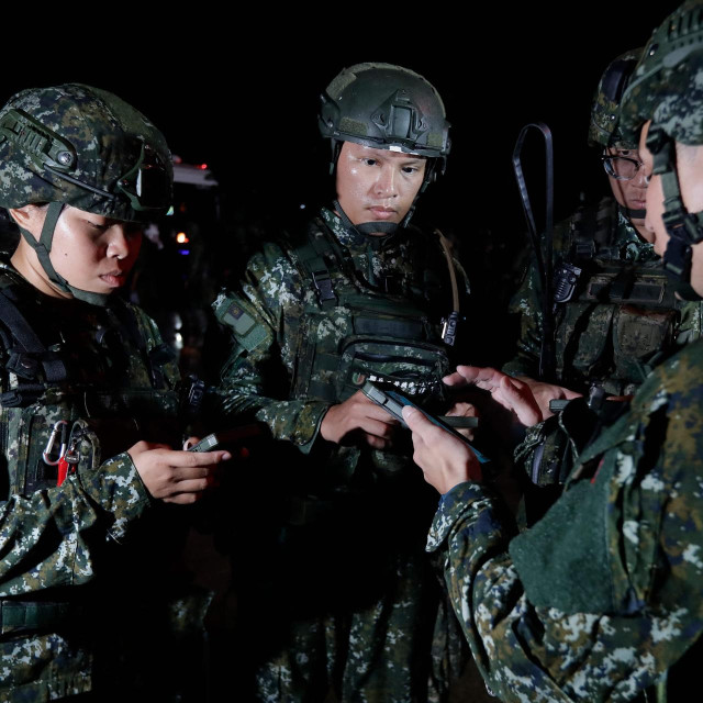 Taiwanese soldiers use phones for mission briefing and order issuance before an overnight cross-region deployment from Hualien to reinforce Yilan during the annual Han Kuang military exercises in Hualien on August 9, 2026. (Photo by Chiang Ying-ying/POOL/AFP)