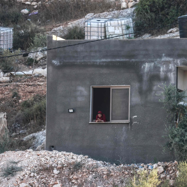Palestinka gleda u svoj mobitel dok se izraelski vojnici (ne vide se) okupljaju u blizini nakon napada dronom u kojem su ubijena tri Palestinca na zapadnom rubu sjevernog grada Jenina, na okupiranoj Zapadnoj obali, 28. kolovoza 2026.