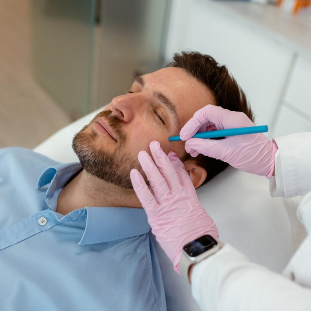 A Cosmetic Specialist Carefully Outlines Areas for Wrinkle Treatment on a Male Client‘s Face Before Administering Facial Fillers or Botox. Man Taking Time for Skincare Aligns With the Growing Trend of Men‘s Grooming and Self-care, Making the Images More Relevant in Today‘s Beauty Industry. These Photos Would Work Great for Industries Like Cosmetic Clinics