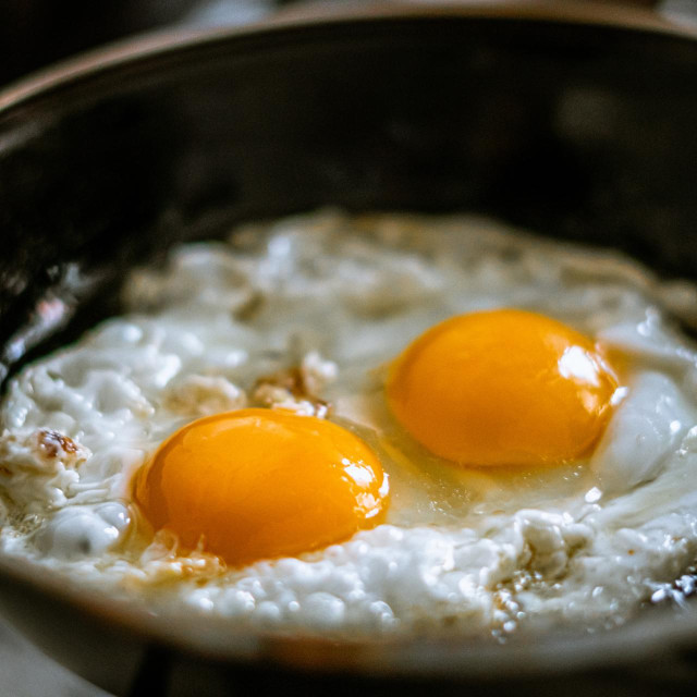 Two eggs frying in a pan with oil