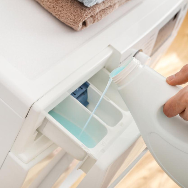 Person pouring washing gel in wachine machine