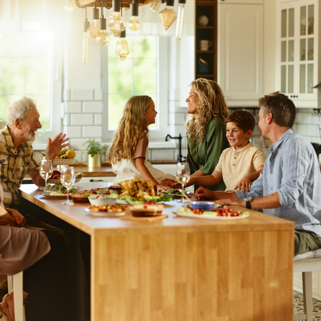 Happy extended family communicating while having lunch in the kitchen.