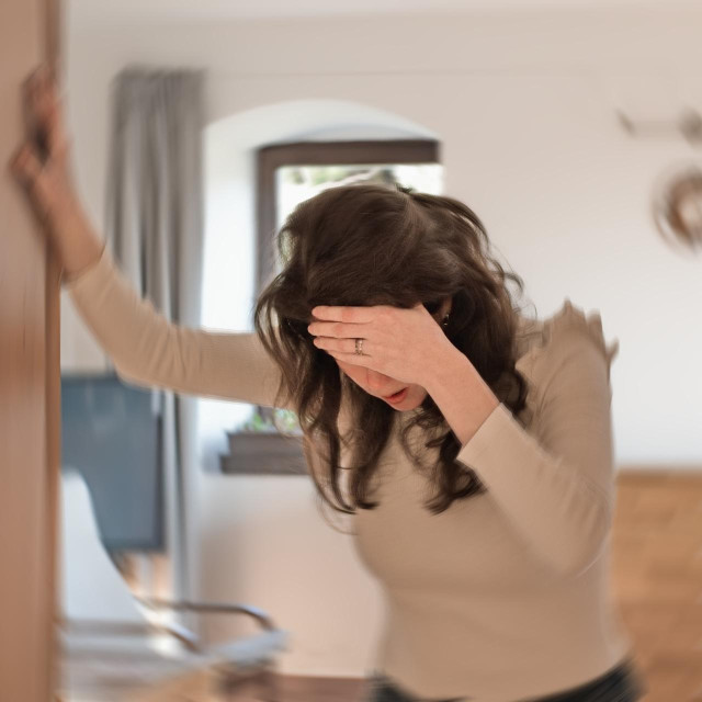 Blured photo of a woman suffering from vertigo or dizziness or other health problem of brain or inner ear.