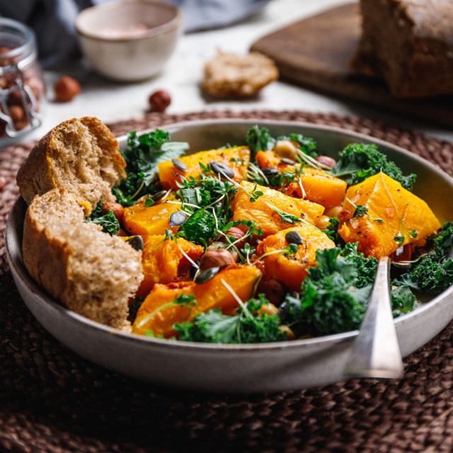 Season salad with grilled pumpkin, kale, chickpea, pepitas and nuts. Autumn vegetarian healthy recipe.
