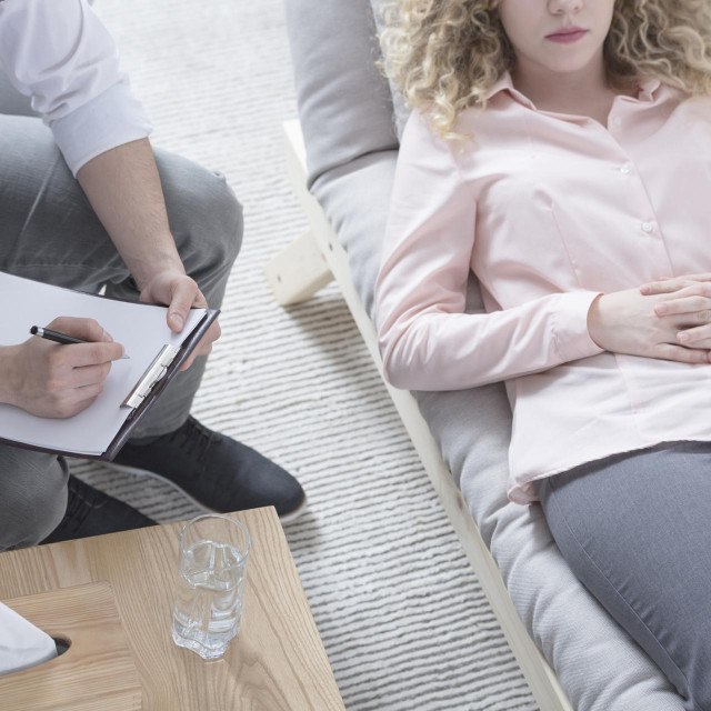 Woman in hypnosis lying on psychotherapist sofa